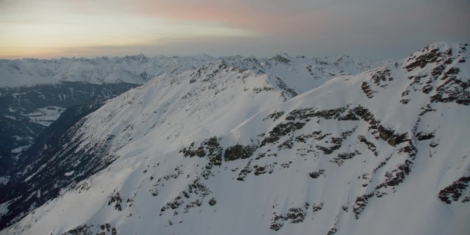 The sun sets over snowy mountains