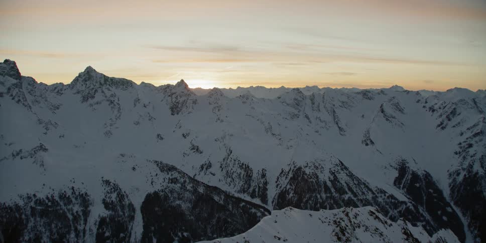 The sun shines above the snowy mountains