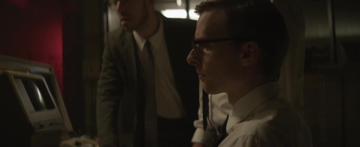 Men stand before a device examining it