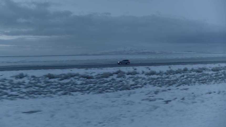 Car drives along a snow covered plain