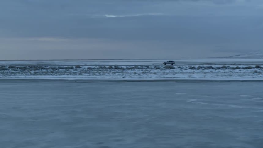 A car drives on a snowy rural road