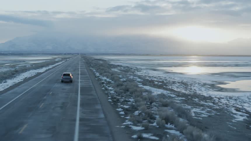 A car travels on a rural road at sunset
