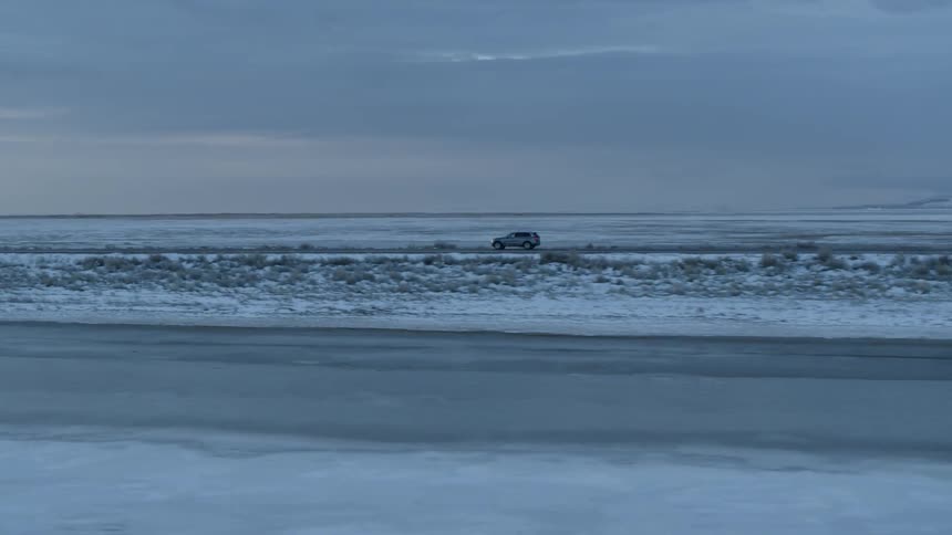 A car drives on a rural road at sunset