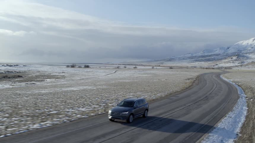 Car drives along snow covered plain
