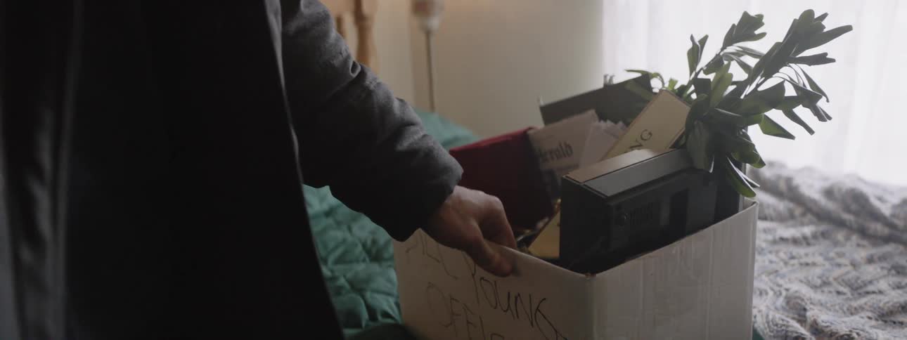 A man looks inside a box on a bed