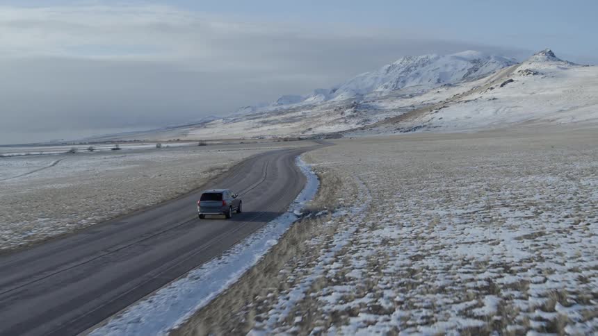 Car drives along snow covered mountain valley