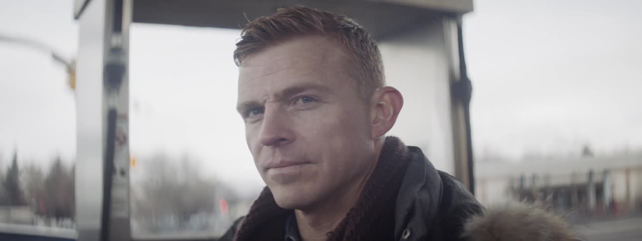 Man smirks while standing outside on a cold day