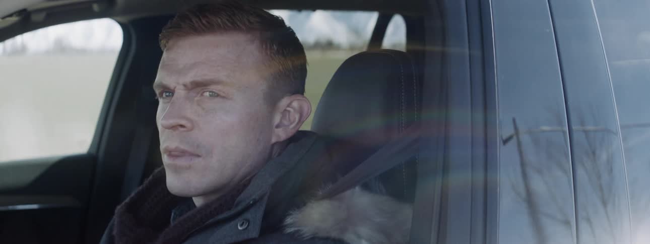 Man looks out the side window while driving a car
