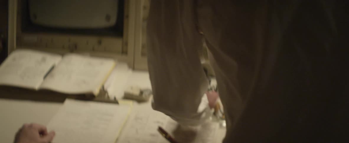 A man approaching a lit control panel and making a phone call