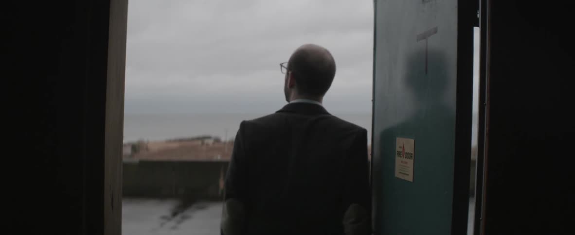 Man opens a metal door and looks up at the sky