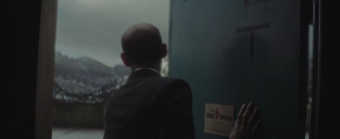 A man opens a door to the outside and sees a snow capped mountain