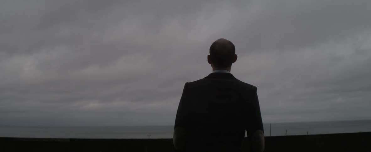 Man looks towards a cloudy ocean