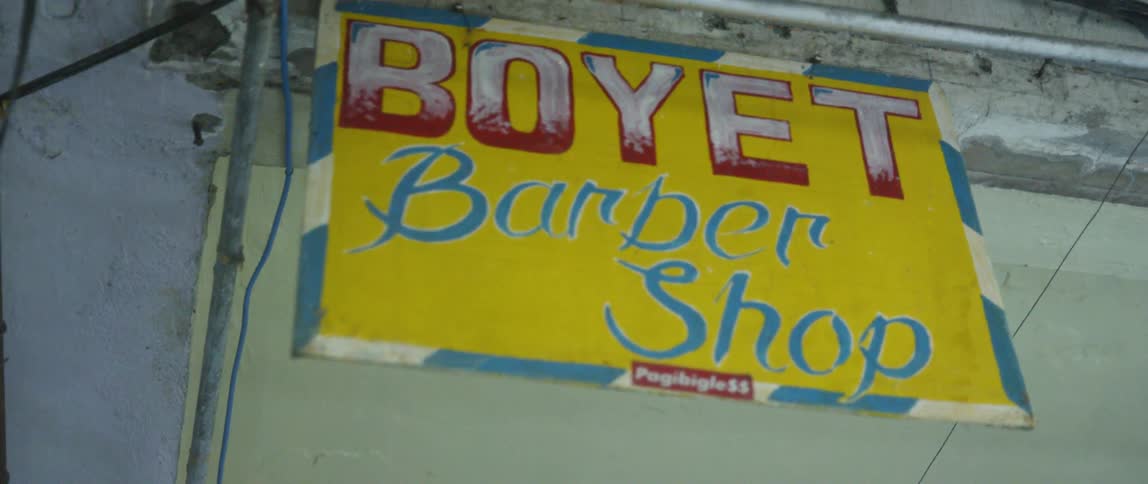 A barbershop sign hangs from a building