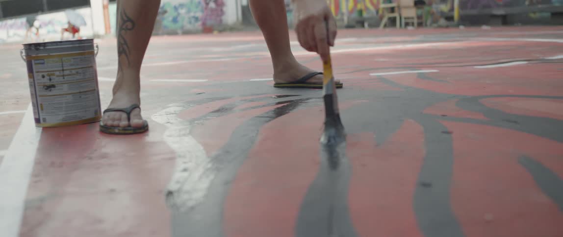 A man is painting a design on the basketball court