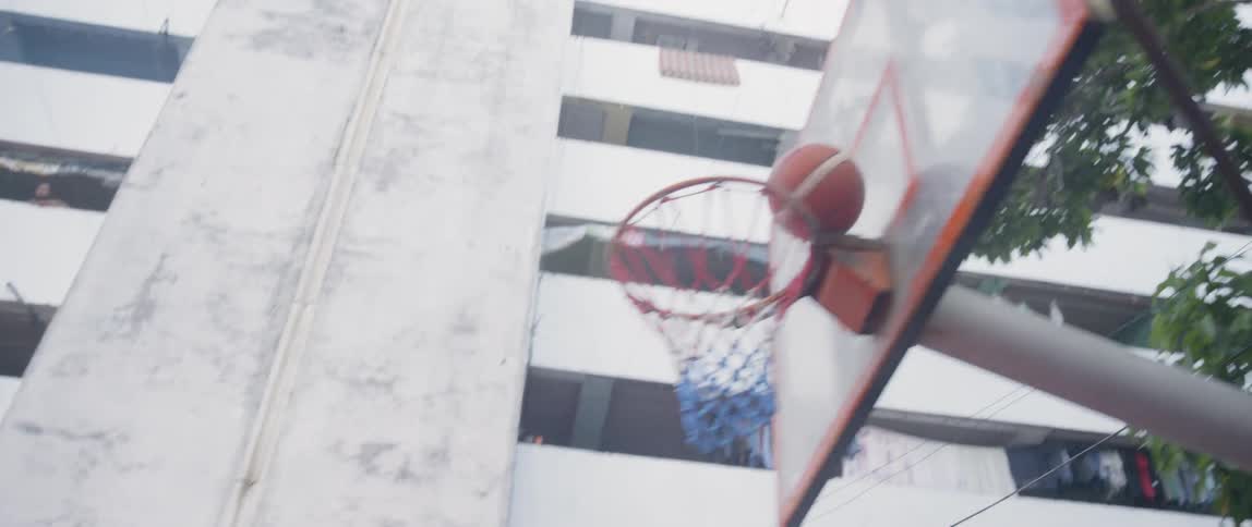 Teenagers play basketball in a courtyard