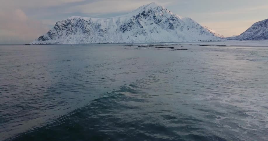 Waves wash ashore a snowy coastline at sunrise