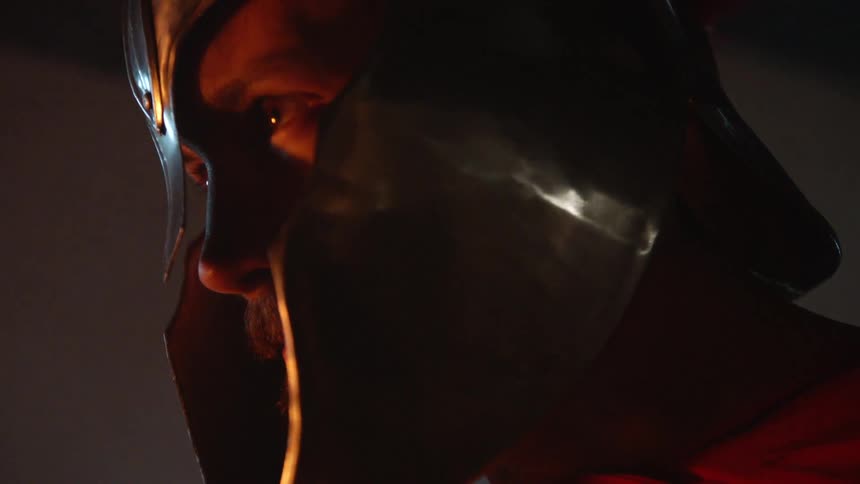 A man wearing a metal helmet looks up at night