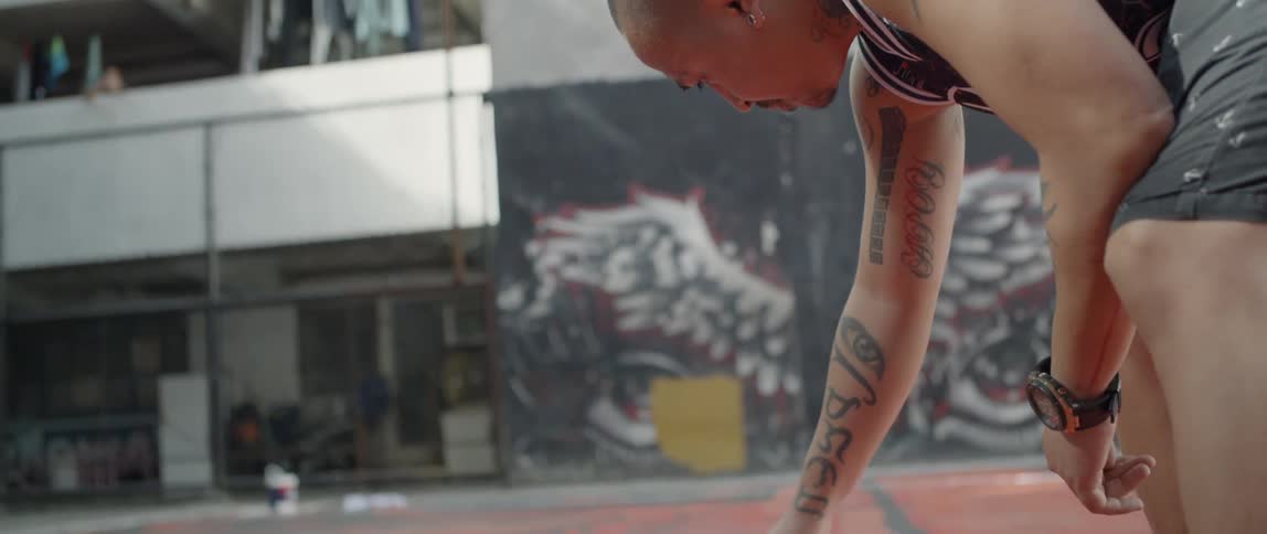 A man paints a black outline onto an outdoor basketball court