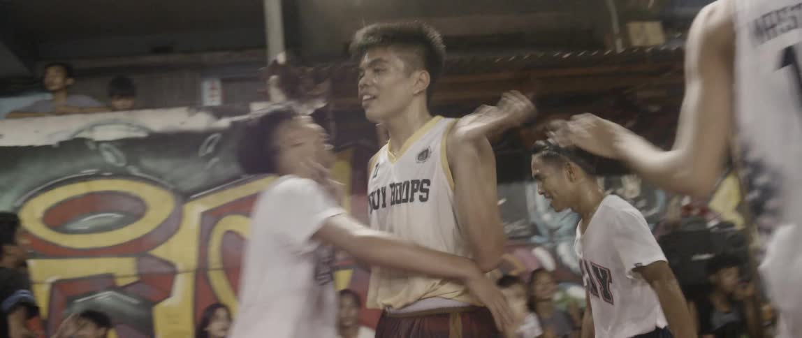 A group of men celebrate on the basketball court