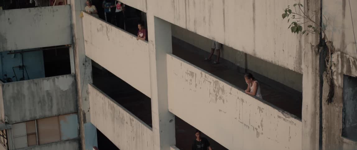 People lean on their balcony walls and look down into the courtyard