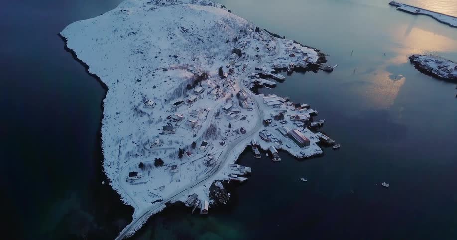 Ocean water surrounds snowy land at sunset