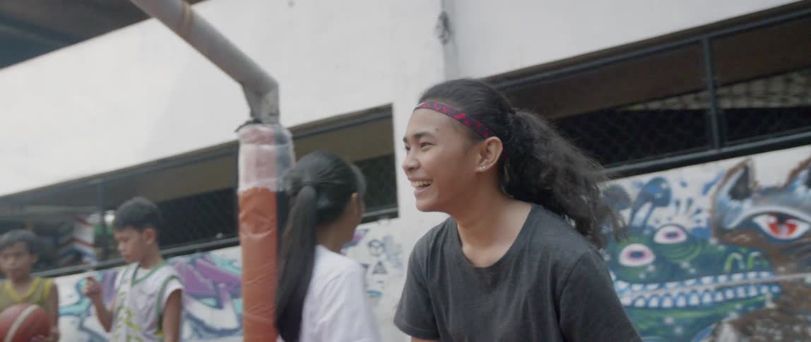 Girls laugh and high five on an outdoor basketball court
