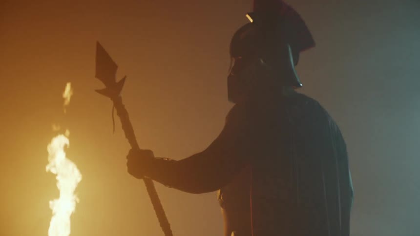 A gladiator stands next to a fire
