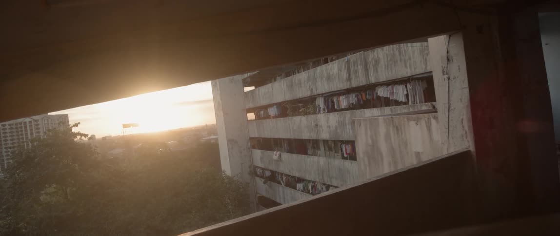 The sun sets behind an apartment building