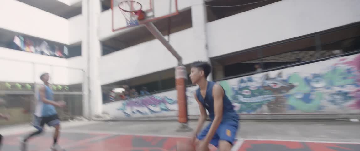 Teenagers play on an outdoor basketball court