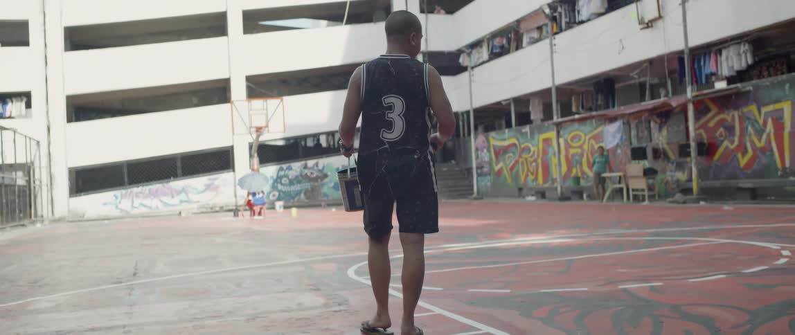 Man carries a bucket as he walks near a building