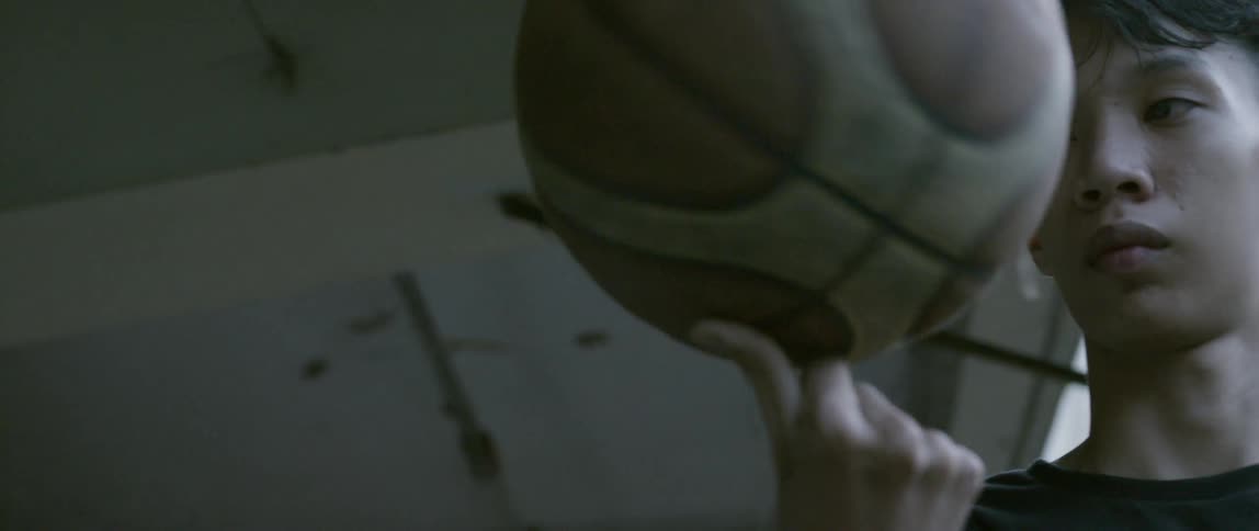 A boy holds and twirls a basketball while standing on a balcony