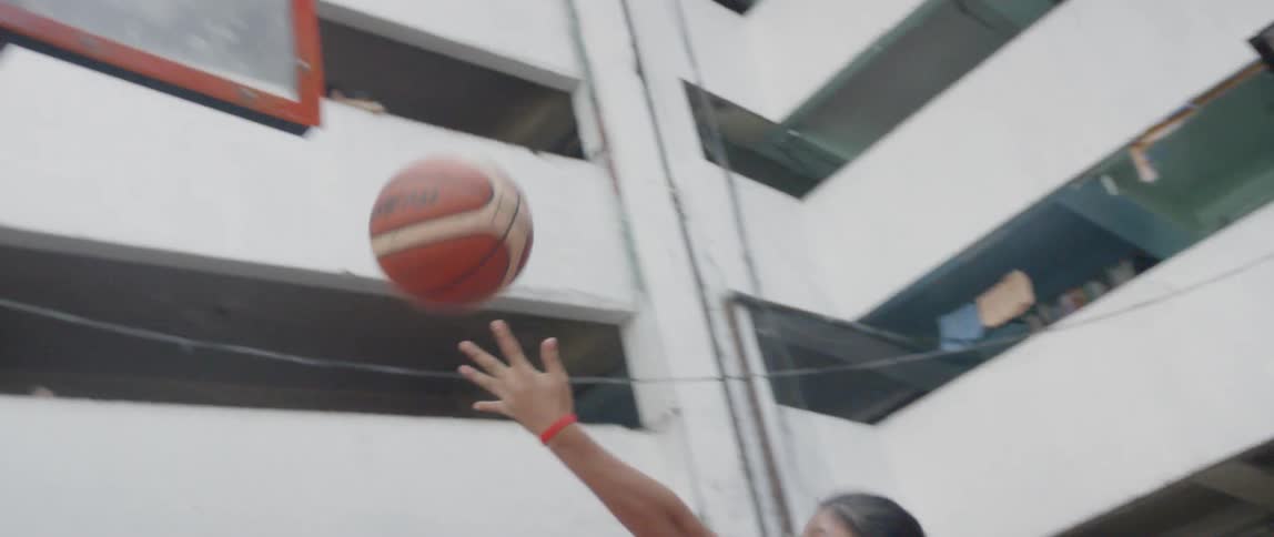 Kids play basketball and one shoots a hoop