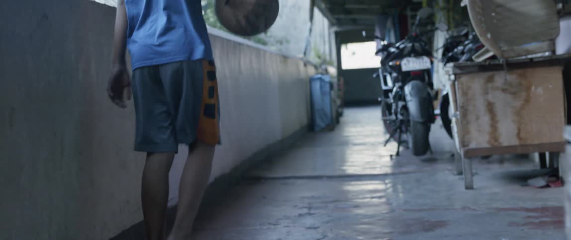 A boy dribbles a basketball as he walks on a porch