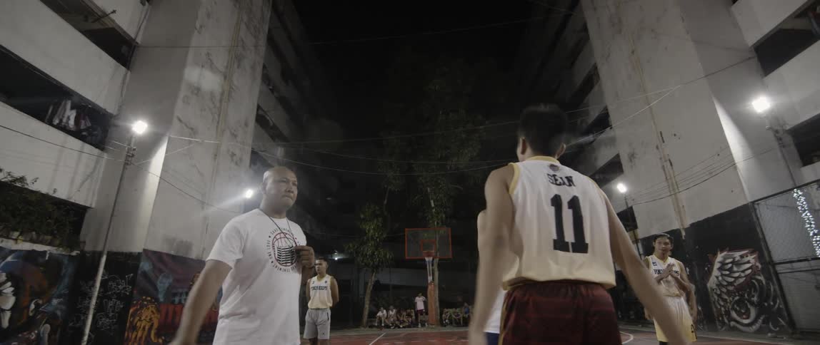 Teenagers play basketball on an outdoor court