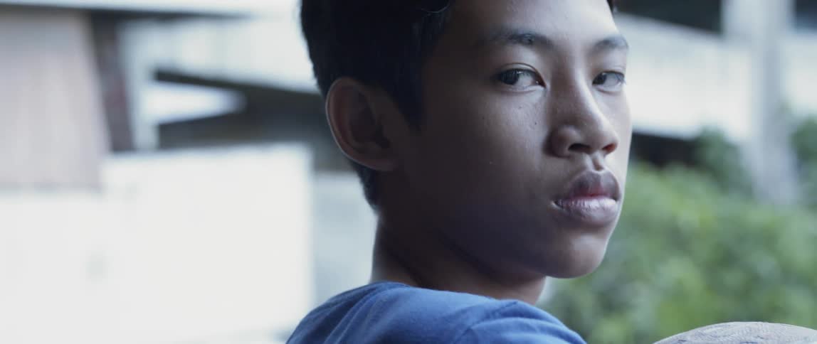 Man holds a basketball as he stares to his right