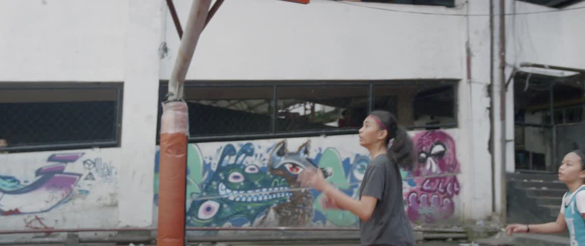 Teenagers play basketball on an outdoor court