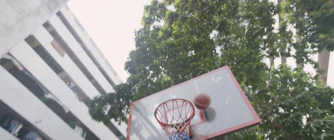 Boys play basketball on a sunny day