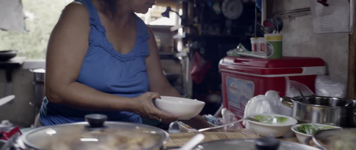Woman scoops noodles into a bowl
