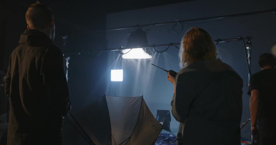 Man holds an umbrella and turns around while a woman holds a walkie talkie nearby