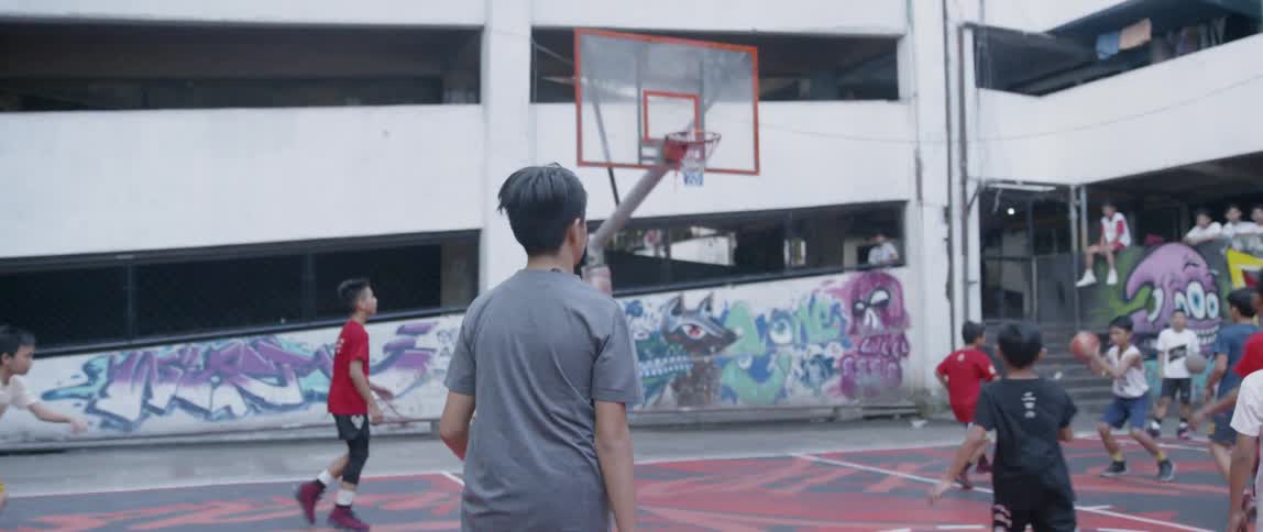 Boys play on an outdoor basketball court