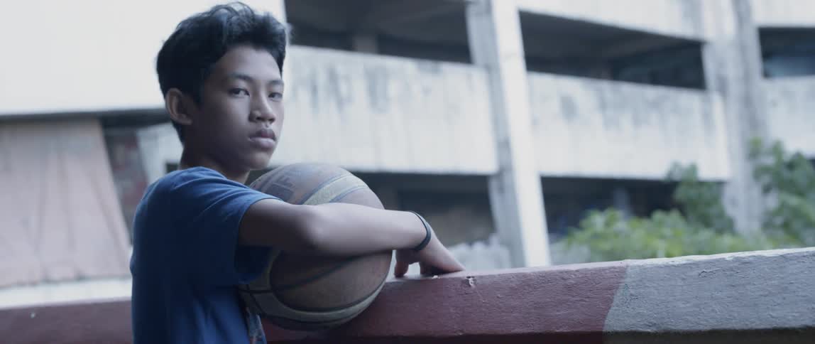 Boy holds a basketball on an apartment balcony