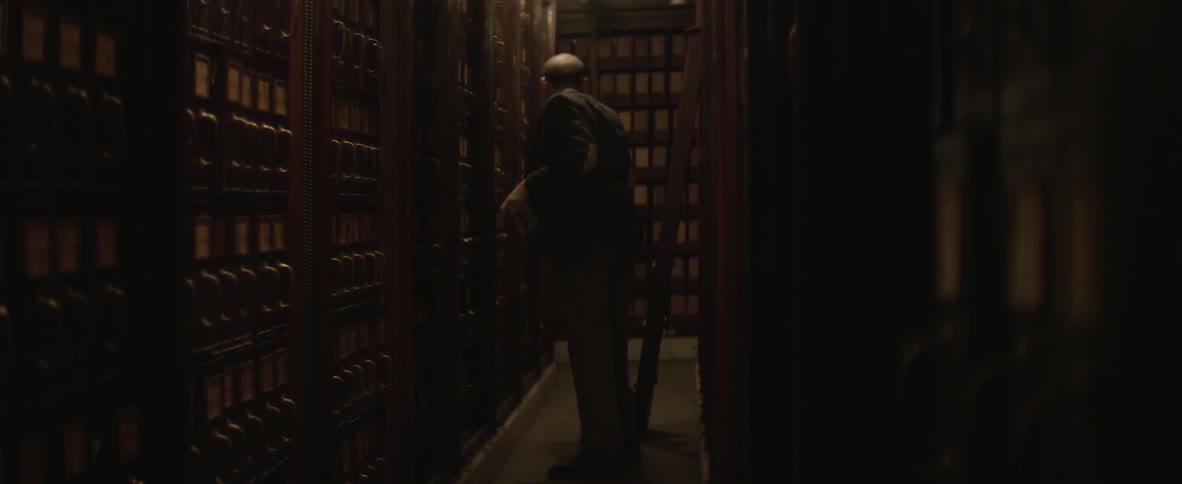 A man removes a stack of papers from the shelving units