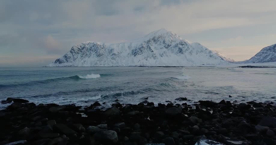 Snow covered rocks sit next to the ocean