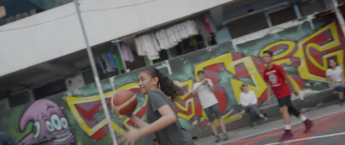Teenagers play basketball on an outdoor court