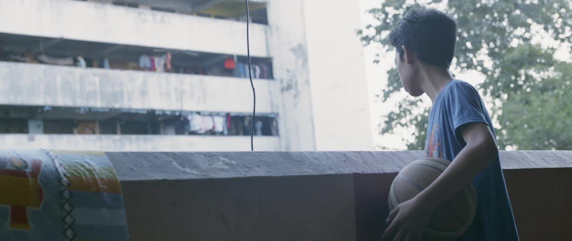 Boy holds a basketball on an apartment balcony