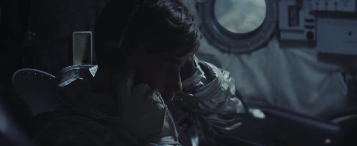 An astronaut in a space capsule adjusts his headset