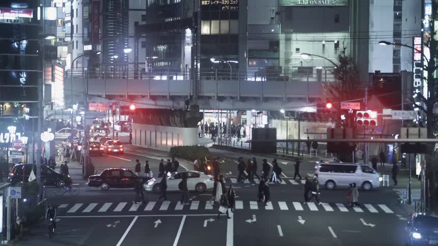 Pedestrians cross a city street at night