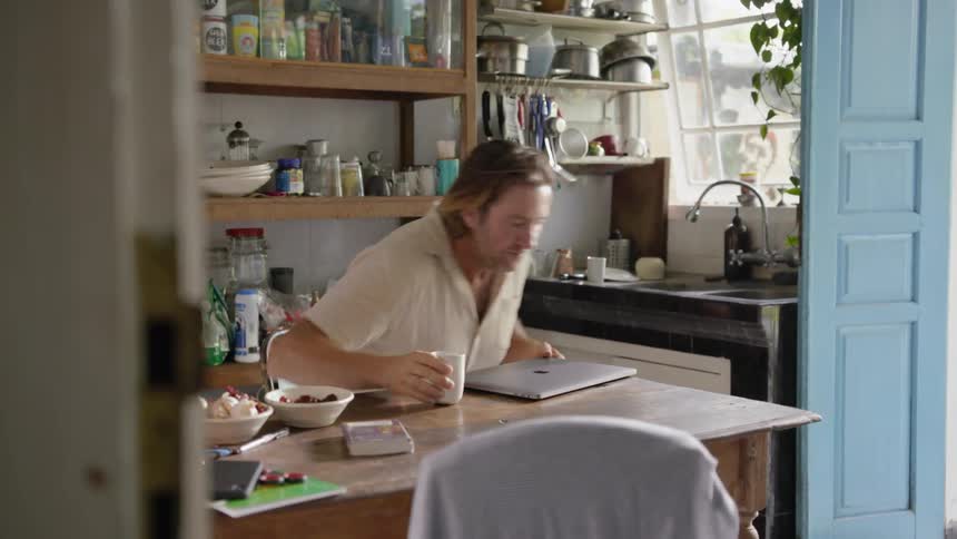 Man drinks from a mug in a kitchen
