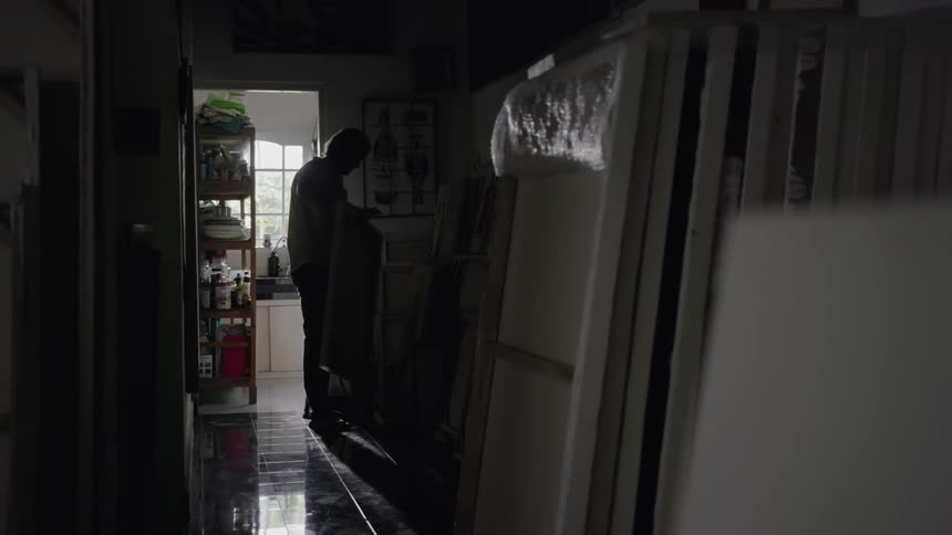 Man picks up a large canvas in an art studio