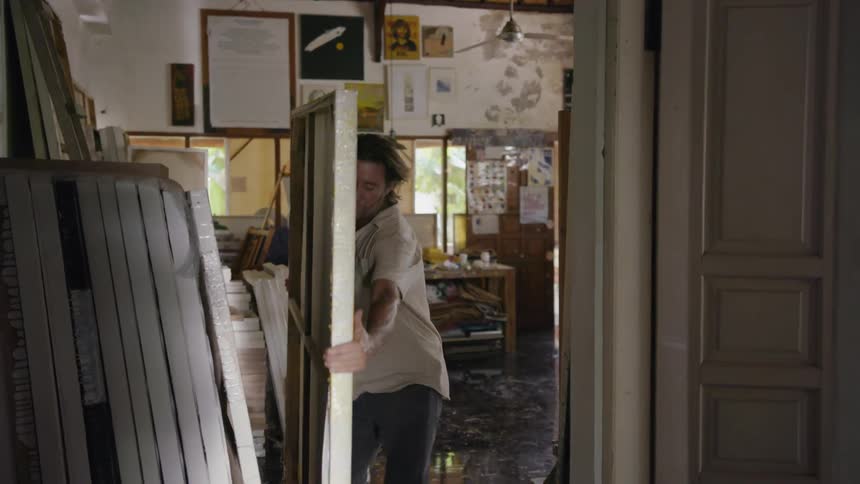 A man moves a large canvas painting